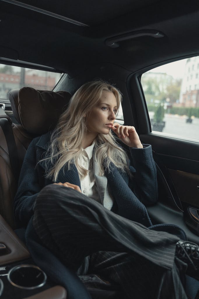 A thoughtful businesswoman sits in a luxurious car, pondering during a ride.