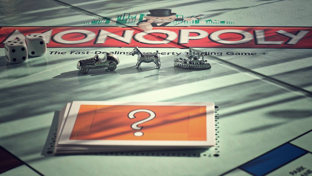 Close-up of Monopoly board game with metal tokens and dice in warm light.